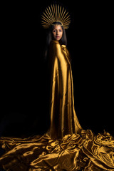 South Asian woman wrapped in gold fabric and wearing a gold headdress