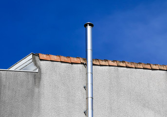 Partial view of a modern house with chimney against blue sky