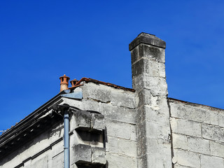 Partial view of a typical ancient house with chimney against blue sky