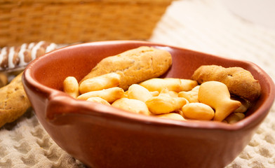 different types of cookies in a clay plate and on a tablecloth.