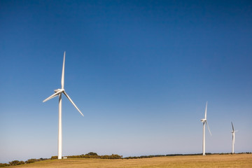 Three tall wind turbines under blue sky with copy space - clean energy concept