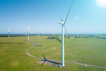 Bright sunlight with flare shining on wind turbines in the countryside - aerial view