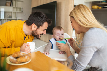 Obraz na płótnie Canvas Parents feeding baby together