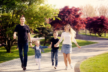 Happy children and parents as a family running in nature in the park in spring