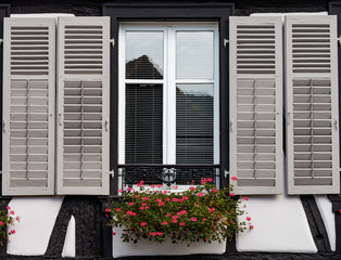 Classic Alsatian windows in a half-timbered house, decorated with wooden carvings and flowers