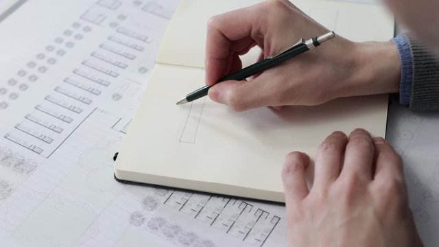 Architect's hands drawing a sketch in his notebook