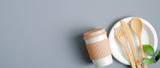 Eco friendly bamboo cutlery and reusable coffee cup on grey background. Zero waste flatware concept. Top view, copy space. Eco shop banner design