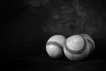 Group of old rugged baseballs with black texture background, copy space for vintage sport concept.