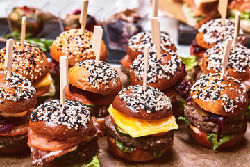 Set of homemade delicious hamburgers made of beef, bacon, cheese, salad and tomatoes on a dark concrete background. Fat junk food close up. With copy space. Fast food pattern
