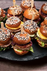 Set of homemade delicious hamburgers made of beef, bacon, cheese, salad and tomatoes on a dark concrete background. Fat junk food close up. With copy space. Fast food pattern
