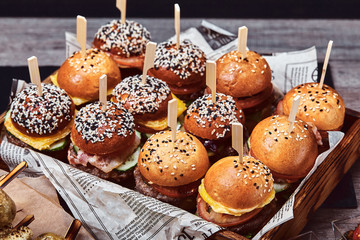 Set of homemade delicious hamburgers made of beef, bacon, cheese, salad and tomatoes on a dark...