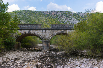 Fototapeta na wymiar Old stone bridge and dry riverbed in hot summer. Knin in Croatia.