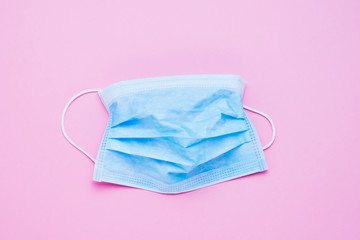 Medical protective mask on pink background. Healthcare and medical concept. Top view, copy space