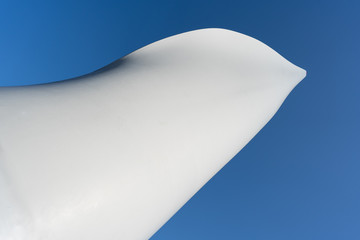 White wing of a pinwheel with blue sky in the background, closeup wind mile