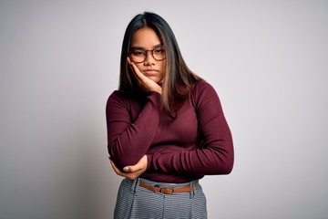 Beautiful asian business woman wearing casual sweater and glasses over white background thinking looking tired and bored with depression problems with crossed arms.