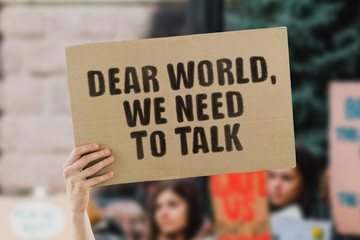 The phrase " Dear world, we need to talk " on a banner in men's hand. Human holds a cardboard with an inscription. Environment pollution. Climate change. Cataclysm. Global warming. Earth. Flooding