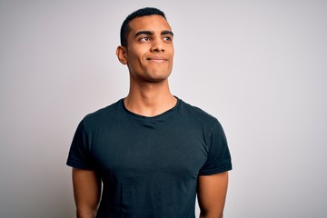 Young handsome african american man wearing casual t-shirt standing over white background smiling looking to the side and staring away thinking.