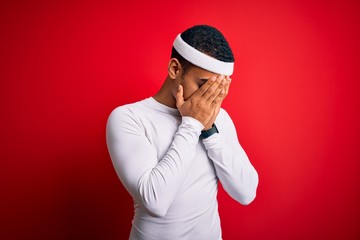 Young handsome african american sportsman wearing sportswear over red background with sad expression covering face with hands while crying. Depression concept.