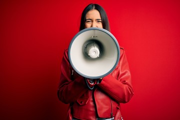 Hispanic woman shouting angry on protest through megaphone. Yelling excited on ludspeaker talking...
