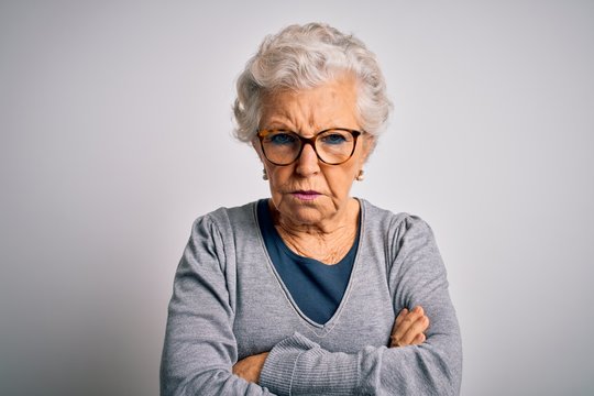Senior beautiful grey-haired woman wearing casual sweater and glasses over white background skeptic and nervous, disapproving expression on face with crossed arms. Negative person.