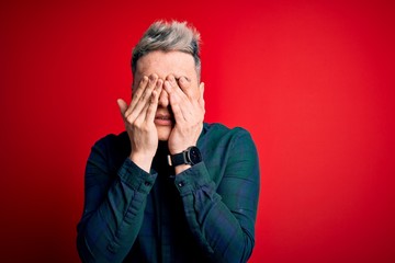 Young handsome modern man wearing elegant green shirt over red isolated background rubbing eyes for fatigue and headache, sleepy and tired expression. Vision problem