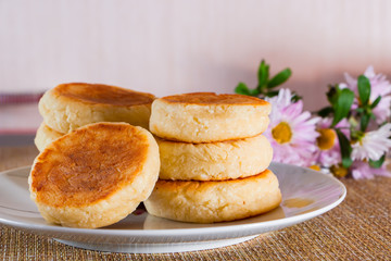 Cheesecakes on a plate on a brown background. Dish of cottage cheese for breakfast.