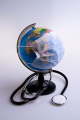 Protective surgical face mask on a terrestrial globe model. Coronavirus Concept. Surgical mask with rubber ear straps. Corona virus,  nCoV, covid 19.  Coronavirus outbreak.