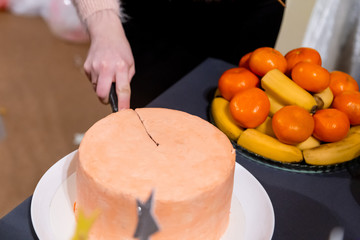 A young girl cuts a peach color cake. The concept of the holiday, wedding, baby shower, birthday