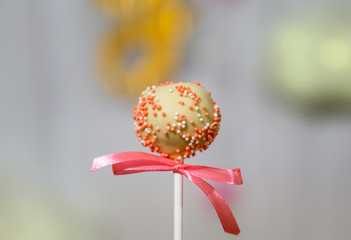 White chocolate cake pop decorated with colorfull confectionery sprinkles on a pastel background....