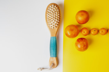 Anti-cellulite brush for dry body massage.   Oranges are laid out in the shape of an arrow. Healthy lifestyle, Prevention of cellulite.
