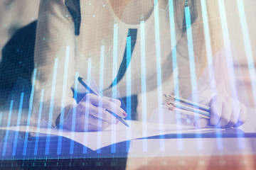 Double exposure of hands making notes with forex chart huds. Stock market concept.
