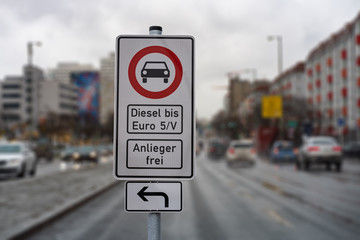 german street sign diesel driving ban in the downtown with a blurred background of city traffic, cars, traffic lights and buildings