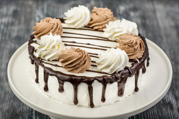 Dessert biscuit cake with sour cream and walnut sprinkle on a white napkin