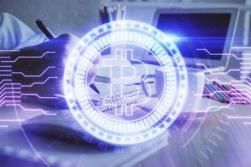 Cryptocurrency hologram, bitcoin, ico theme over hands taking notes background. Concept of...