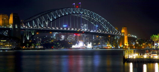 Sydney Harbour Bridge illuminating the harbour and circular quay with vibrant colourful lights at midnight in NSW Australia