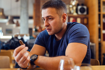 Portrait of young adult caucasian man sitting alone at the table at bar or restaurant wearing blue...