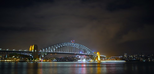 Obraz premium Sydney Harbour Bridge illuminating the harbour and circular quay with vibrant colourful lights at midnight in NSW Australia