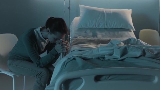 Sad woman crying next to an empty hospital bed