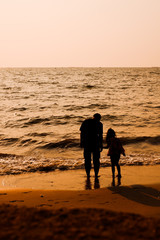 The silhouette of father and daughter playing together on the beach by the sea.