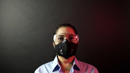 Woman in urban protective or medical mask with glasses, looking at the camera on black background. Coronavirus pathogen outbreak pandemic concept. Virus disease 2019-nCoV protection and prevention.