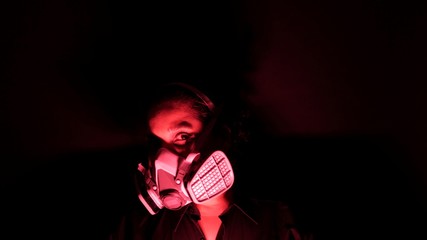 Woman in the heavy duty biohazard medical mask in the darkness and red light. Personal forced home...