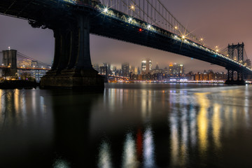 Naklejka premium East River view on a foggy night with Manhattan Bridge,Brooklyn bridge, Financial District long exposur photo