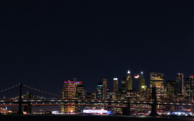 Fototapeta na wymiar View of Downtown Manhattan with a crescent moon at night from the East River