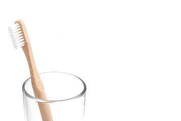 Bamboo toothbrush close-up in glass on white background. Eco friendly and zero waste concept photo.