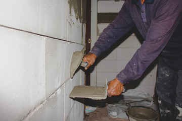 Close-up of a construction worker laying cement on the wall for building a house and building construction.
