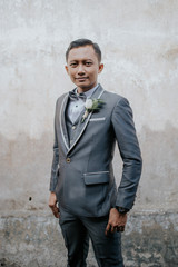 Selective focus of groom is standing with concrete wall background. Wedding concept.