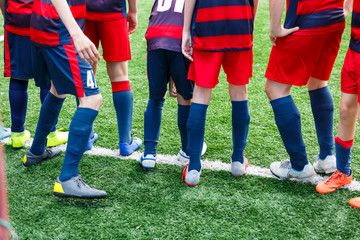 Boys in white and blue sportswear plays  football on field, dribbles ball. Young soccer players with ball on green grass. Training, football, active lifestyle for kids concept 