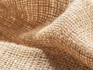 Brown burlap textile. Crumpled sackcloth, close up view. Texture of burlap fabric. Brown baline, abstract background. Selective soft focus. Blurred background