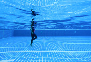 Underwater image of a woman walking in a swimming pool for treatment. underwater background