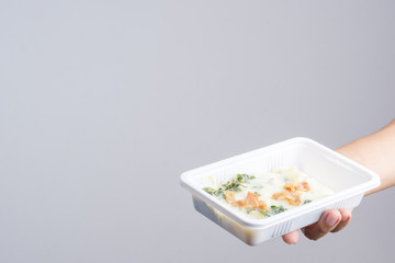 Hand holding spinach with cheese in plastic box